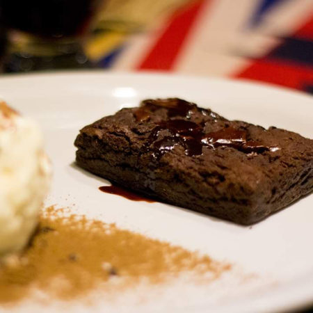 Brownie servido quente com calda de chocolate caseira. Acompanha sorvete de creme.